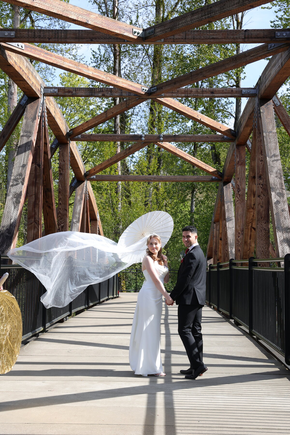 Couple on a forest bridge, veil in the wind